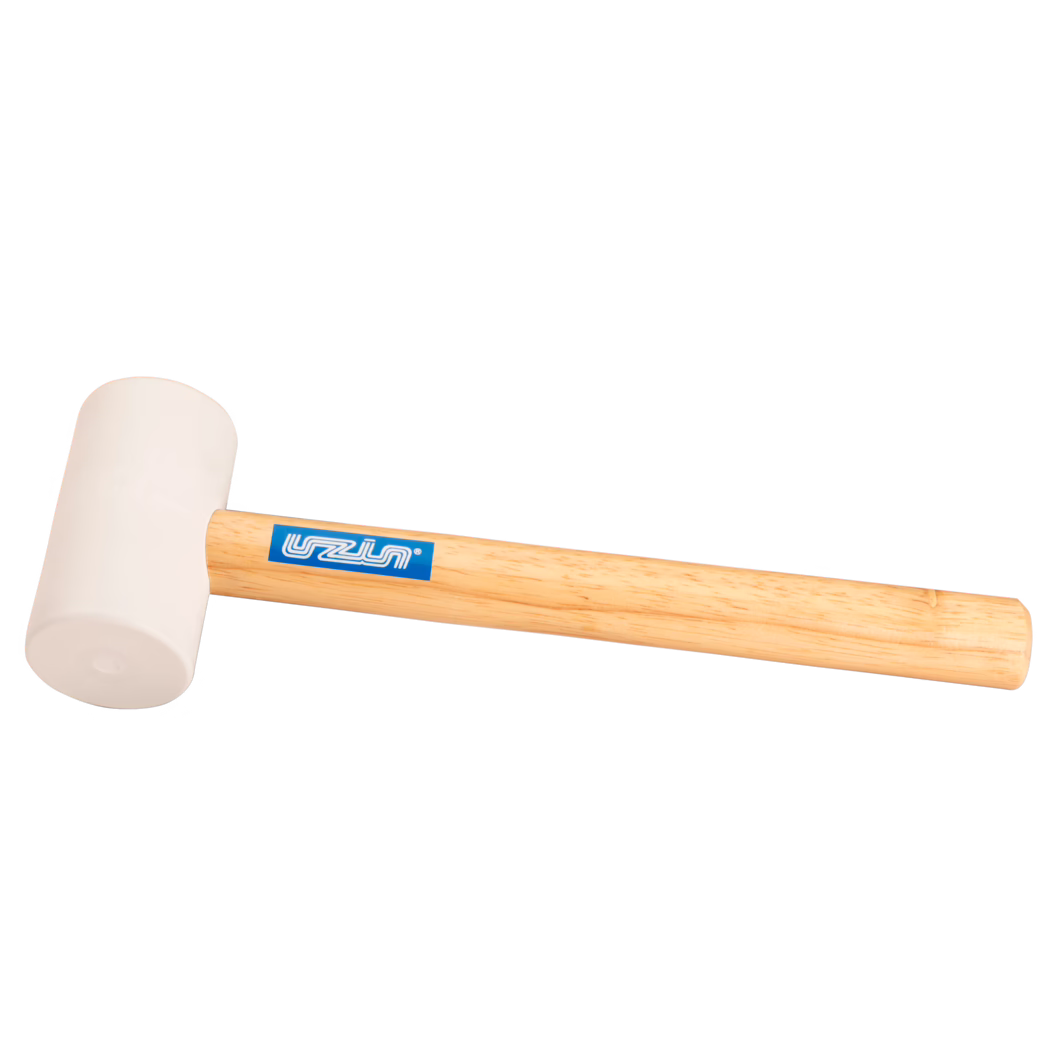 UZIN_Dummy_rubber hammer-UZIN_2014-11 Close-up product image of a rubber mallet: light beige rubber head on a smooth light wooden handle with a blue rectangular brand sticker; positioned diagonally on a white background with soft even lighting that highlights the rubber texture and wood grain; for gentle striking tasks in carpentry and assembly or tile installation.