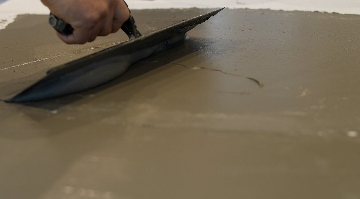 A hand holds a trowel, spreading feather finish over a flat surface during a repair project. A hand holds a trowel, spreading feather finish over a flat surface during a repair project.